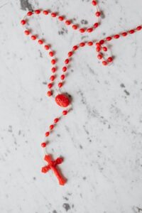 Beautiful red rosary beads laid out on a marble surface, symbolizing faith and spirituality.